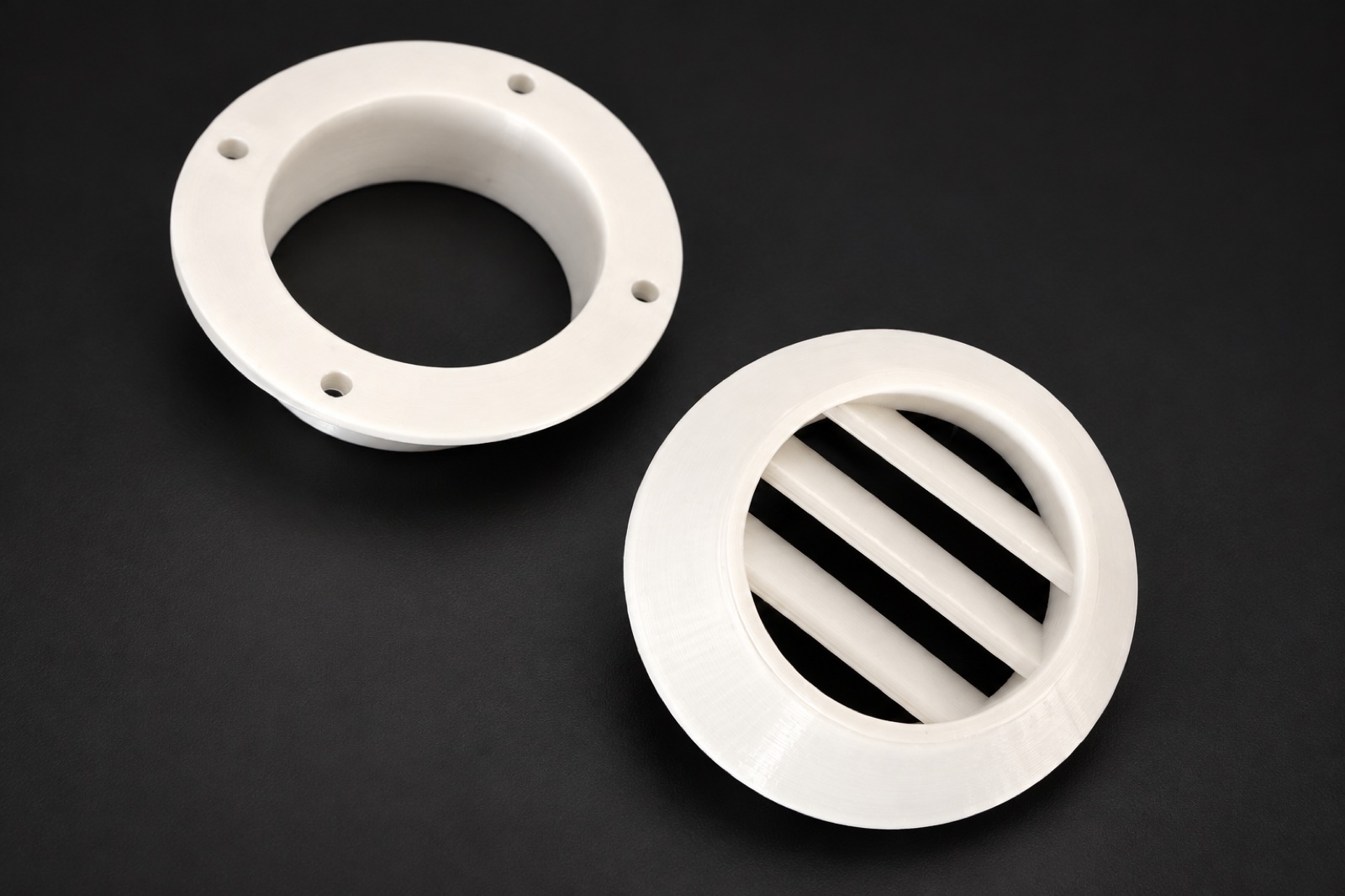 Two white 3D printed circular vent components